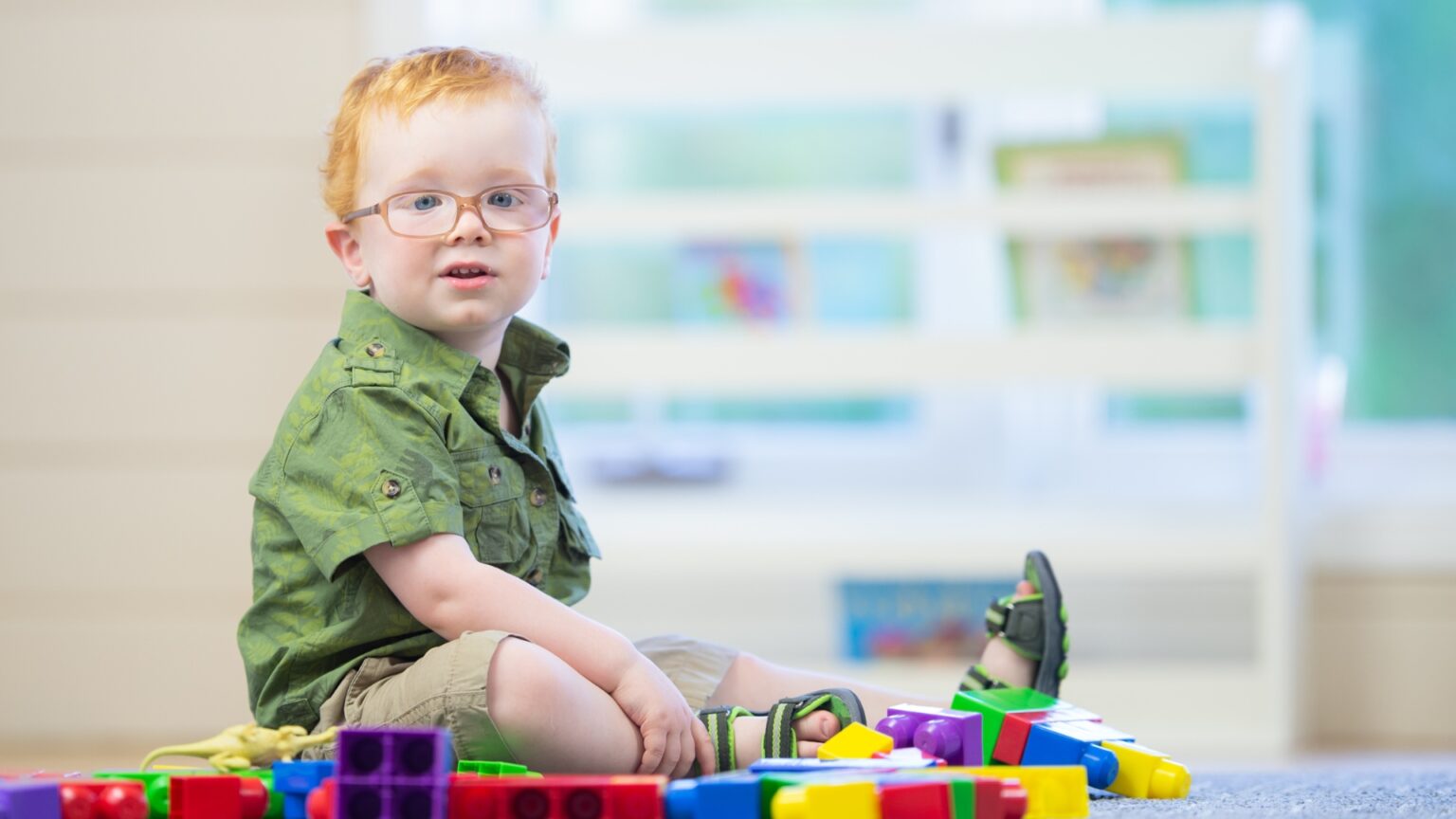 Child with autism sitting on the floor surrounded by toys, engaged in quiet play. The scene highlights focus, imagination, and the role of independent play in child development.