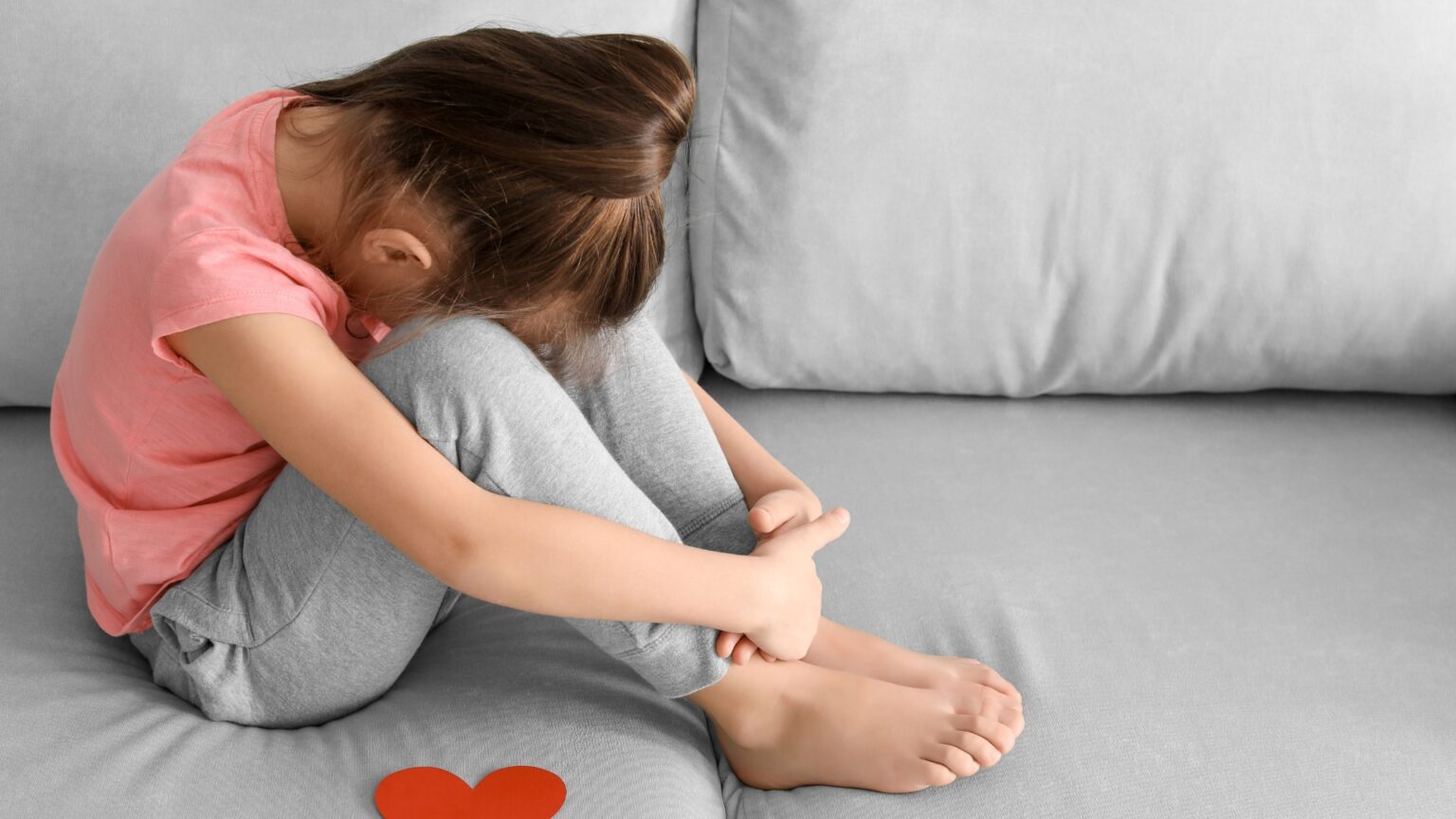 a girl with autism sitting on a couch with her head in her hands